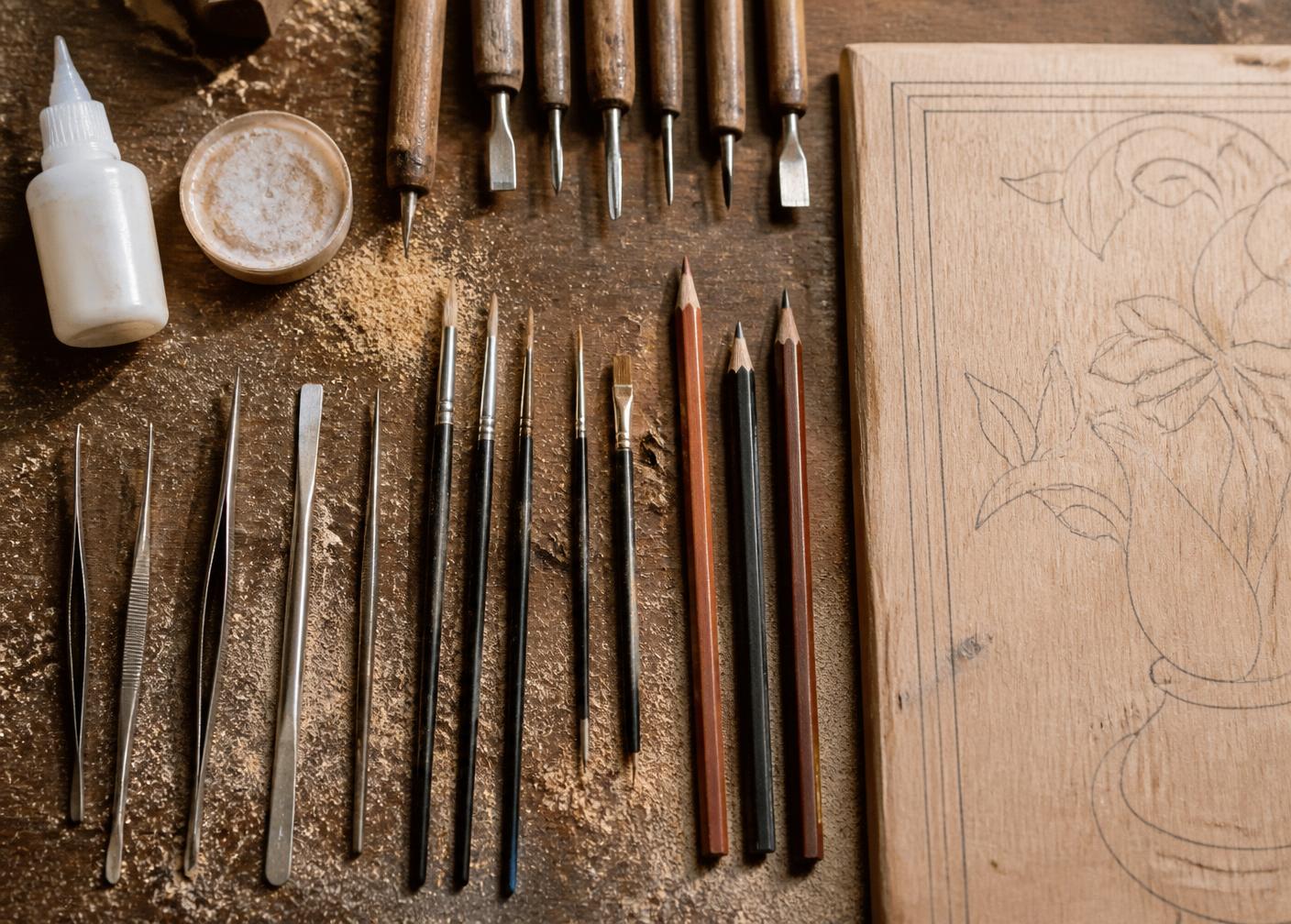 Studio tools: tweezers, spatulas, fine brushes and a drawn wooden panel
